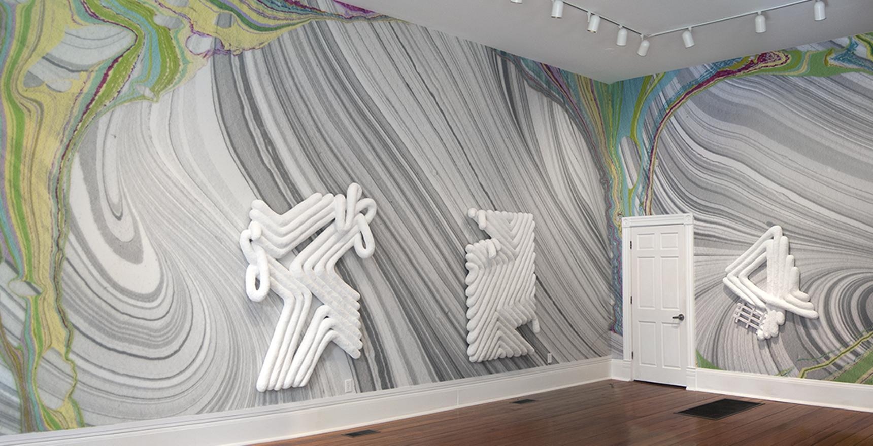 walls painted swirling textures white geometric tubular sculptures hang on walls