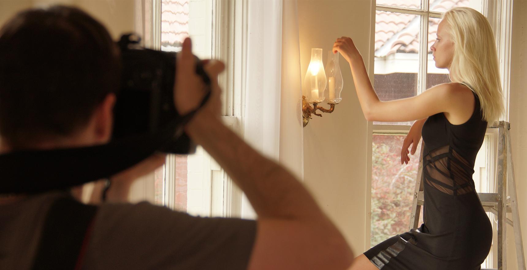 a model being photographed lighting a candle sconce