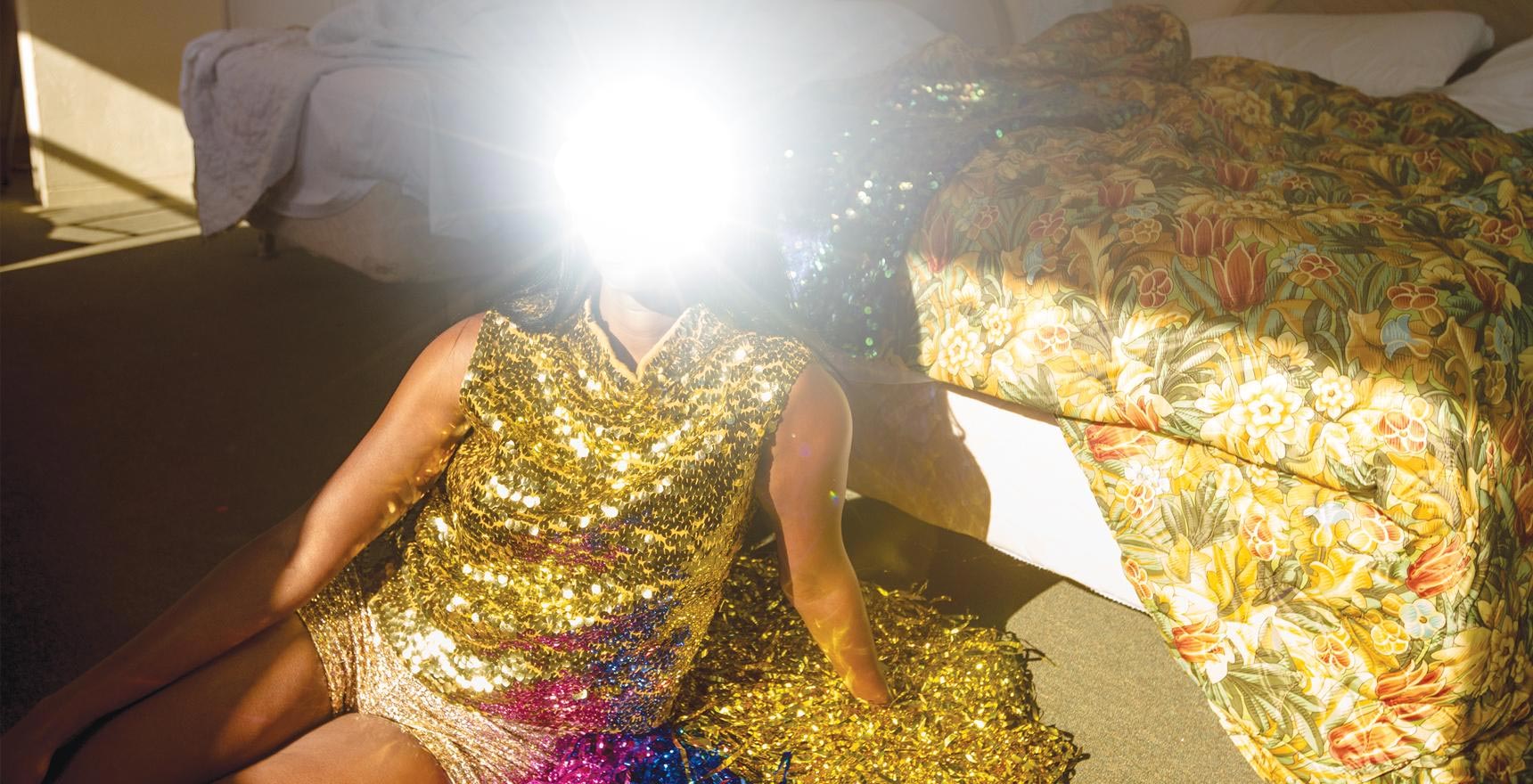 a woman in gold face obscured by bright light