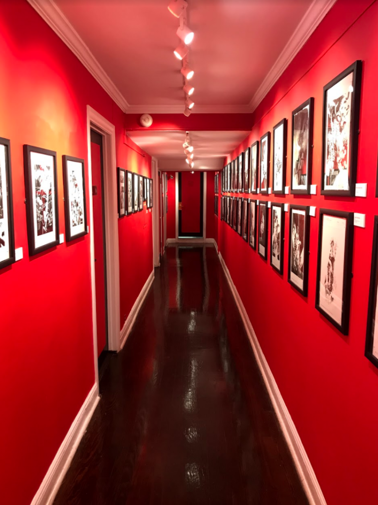 A photo of a hallway hanging many art works