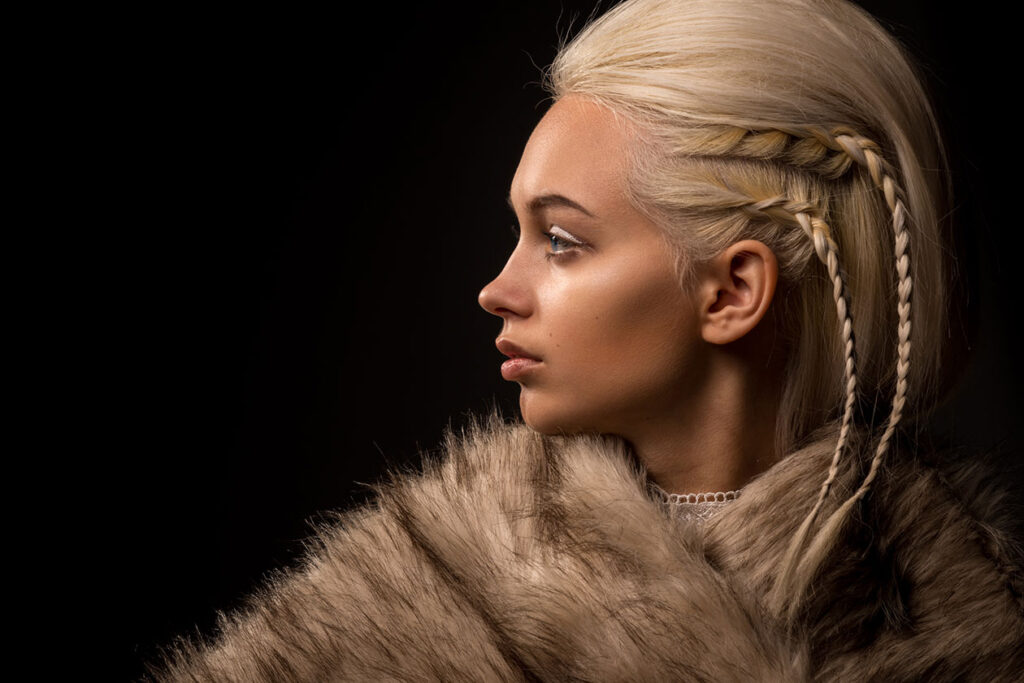 A photo of a blond woman profile in furs and braids