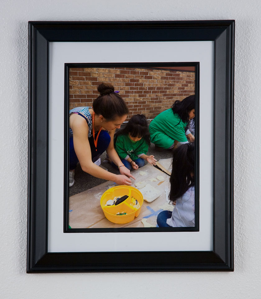 A picture of a framed photo of a woman painting with children
