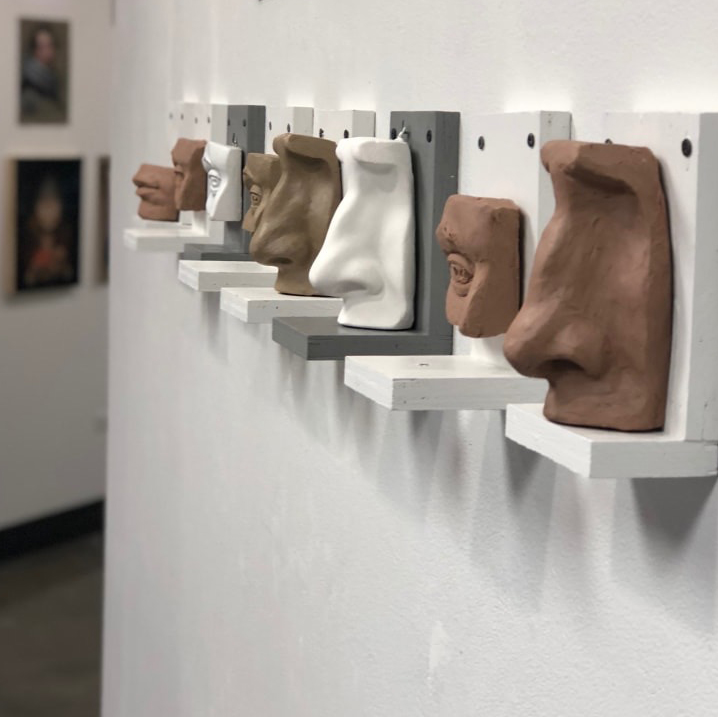 Photo of sculptures of noses and heads on wall hung shelves