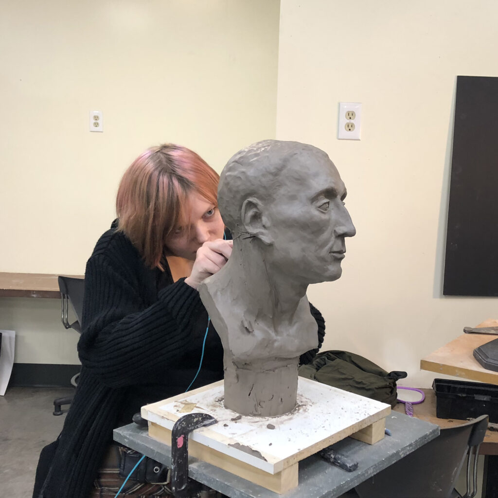 Photo of a sculptor working on the bust of a man